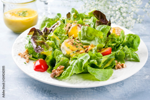 Traditional Germen summer lettuce with curled lettuce, goat cheese and mango dressing as closeup on a plate on a well laid table