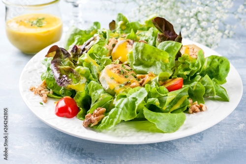 Traditional Germen summer lettuce with curled lettuce, goat cheese and mango dressing as closeup on a plate on a well laid table © HLPhoto