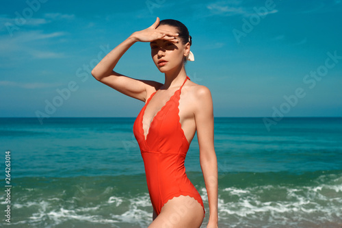 Beautiful sexy woman in red swimwear on the beach