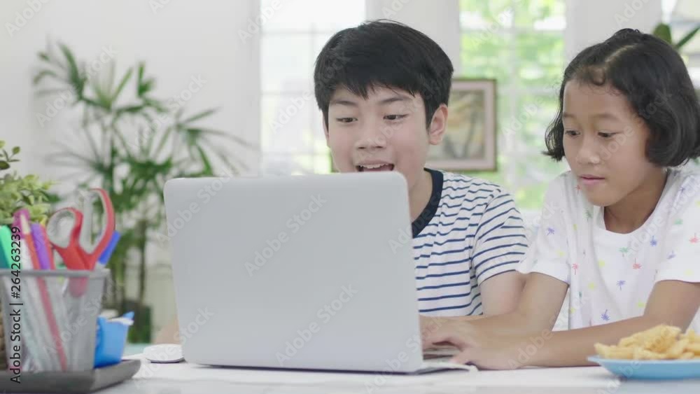 Young asian boy and girl playing with laptop computer at home. Children are playing online game on a laptop computer together. Dolly shot 60fps. Young asian boy and girl playing with laptop computer at home. Children are playing online game on a laptop computer together. Dolly shot 60fps.