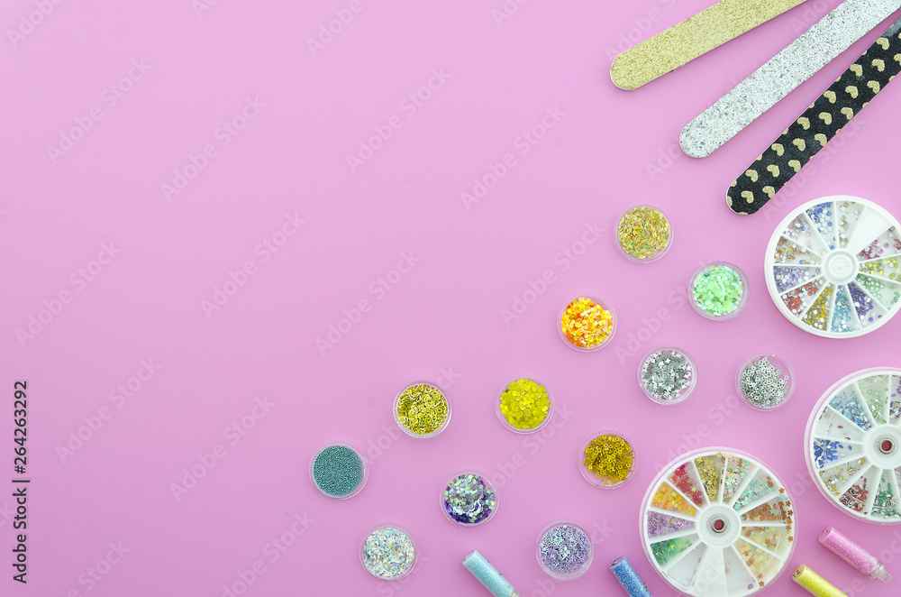Flat lay sequins with nail polish buff on a pink workpspace with copy space on corner