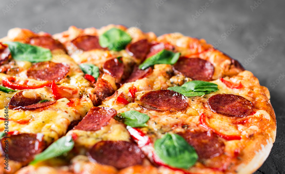 Pepperoni Pizza with Mozzarella cheese, salami, pepper, Spices and Fresh spinach. Italian pizza on Dark grey black slate background Pepperoni Pizza with Mozzarella cheese, salami, pepper, Spices and Fresh spinach. Italian pizza on Dark grey black slate background