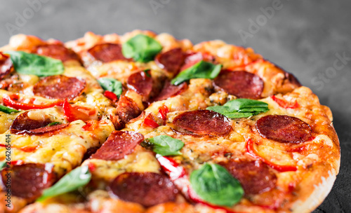 Pepperoni Pizza with Mozzarella cheese  salami  pepper  Spices and Fresh spinach. Italian pizza on Dark grey black slate background