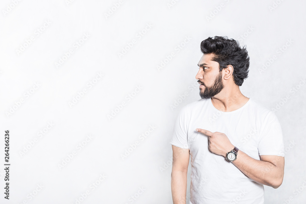 Handsome young man indicates with forefinger at blank copy space. Handsome young man indicates with forefinger at blank copy space.