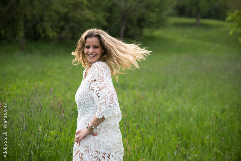 Young happy caucasian woman smiling in a meadow full of flowers. Nature and happiness concepts Young happy caucasian woman smiling in a meadow full of flowers. Nature and happiness concepts