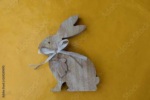 blick auf einen osterhasen aus holz auf gelbem hintergrund fotografiert an Ostern an einem sonnigen Tag im Emsland