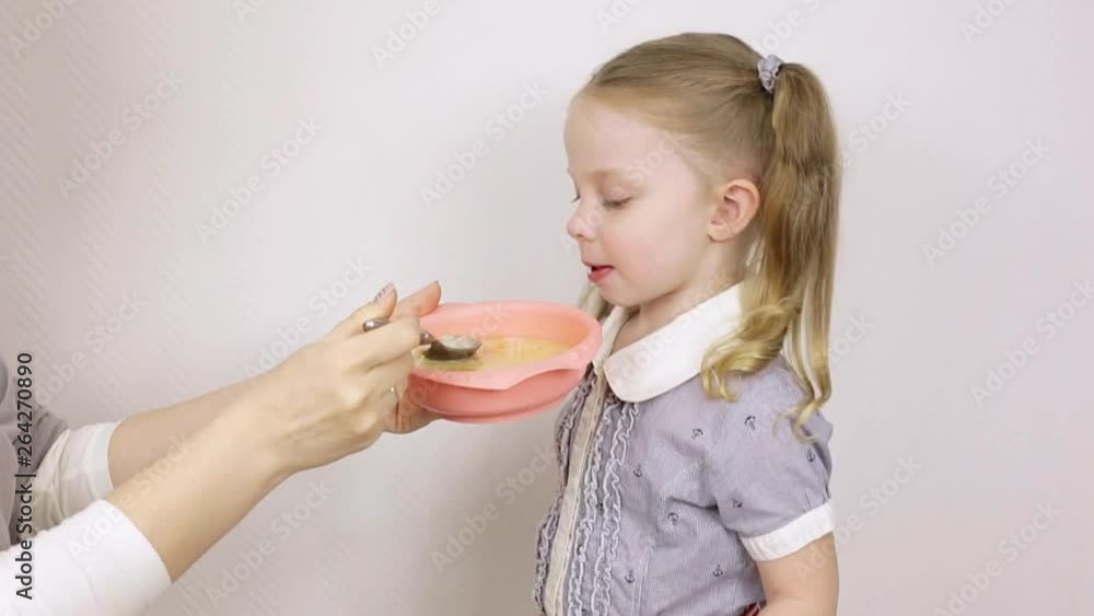 mom feeds little daughter with soup on white background mom feeds little daughter with soup on white background
