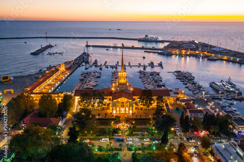 Aerial photography with quadrocopter. Sea port of Sochi with a bird s eye view. Evening illumination of the building. Yachts and boats are in the port. Resort town. Landmark. 