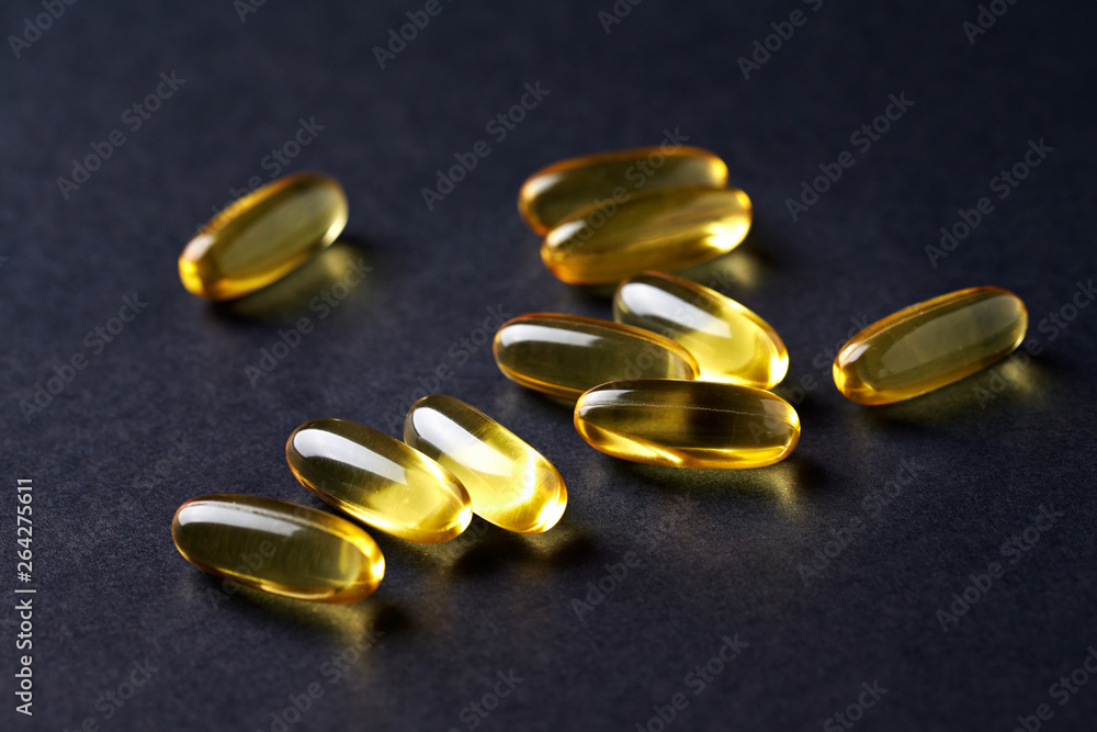 Fish oil capsules with omega 3 on black background. Concept for a healthy dietary supplementation. Immune System Support. Close up. Copy space. D Fish oil capsules with omega 3 on black background. Concept for a healthy dietary supplementation. Immune System Support. Close up. Copy space. D