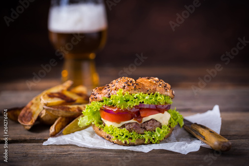 Home made hamburger with green salad on brown wooden background.