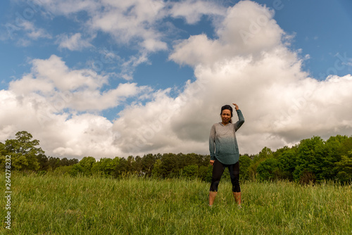 Woman standing in green field with clouds behind