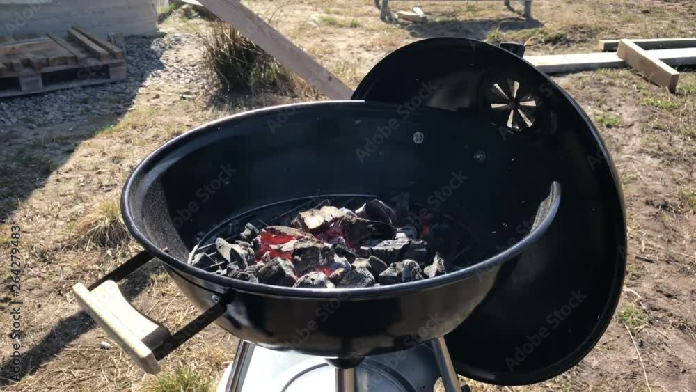 Burning coals and wood on a grill grate. Preparation of coal for barbecue in a large round open grill. The concept of relaxation and enjoyment of food Burning coals and wood on a grill grate. Preparation of coal for barbecue in a large round open grill. The concept of relaxation and enjoyment of food
