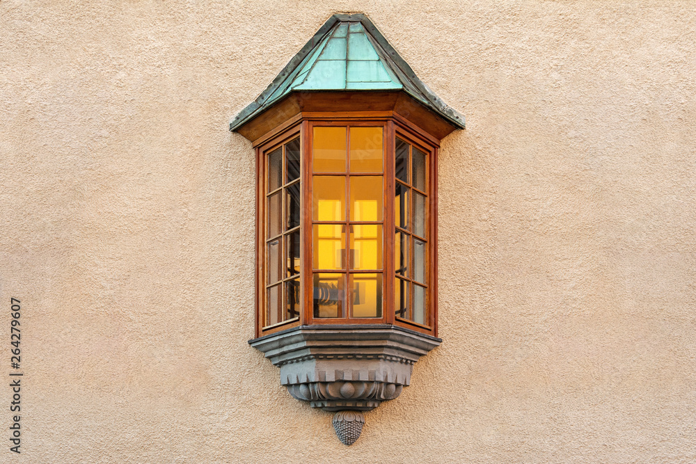 Obraz premium The window in the form of a bay window is located in the middle of the plastered wall of the building