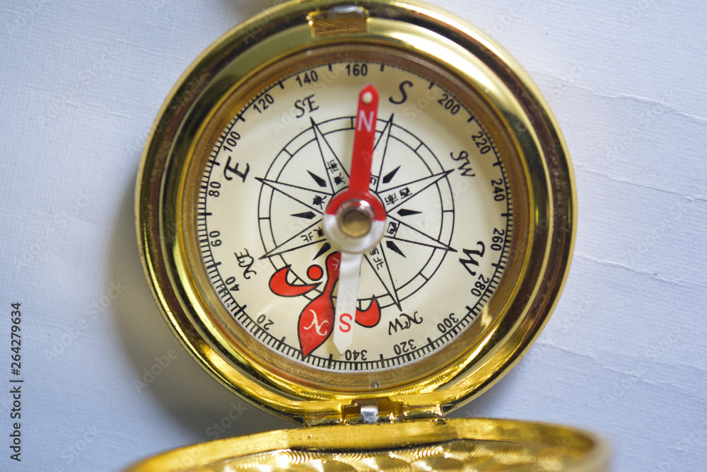 Close up magnetic golden compass isolated on white background.