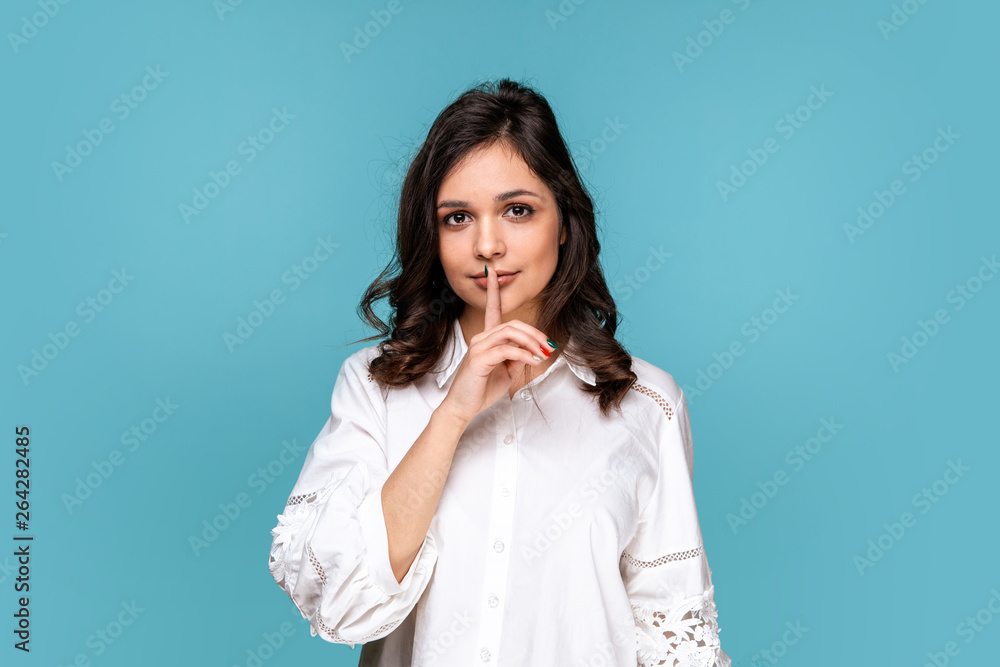 Handsome girl showing to keep silence isolated over the blue background Handsome girl showing to keep silence isolated over the blue background