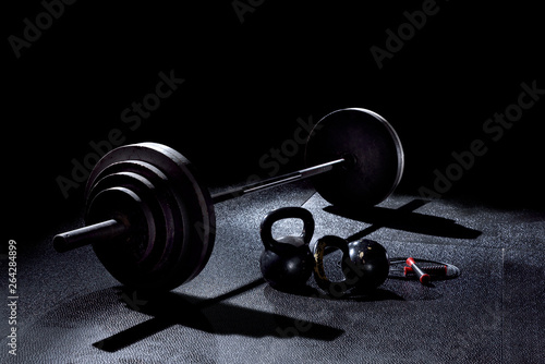 BACK LIT image of 365 pound weight on barbell with kettle bells and jump rope on gym floor
