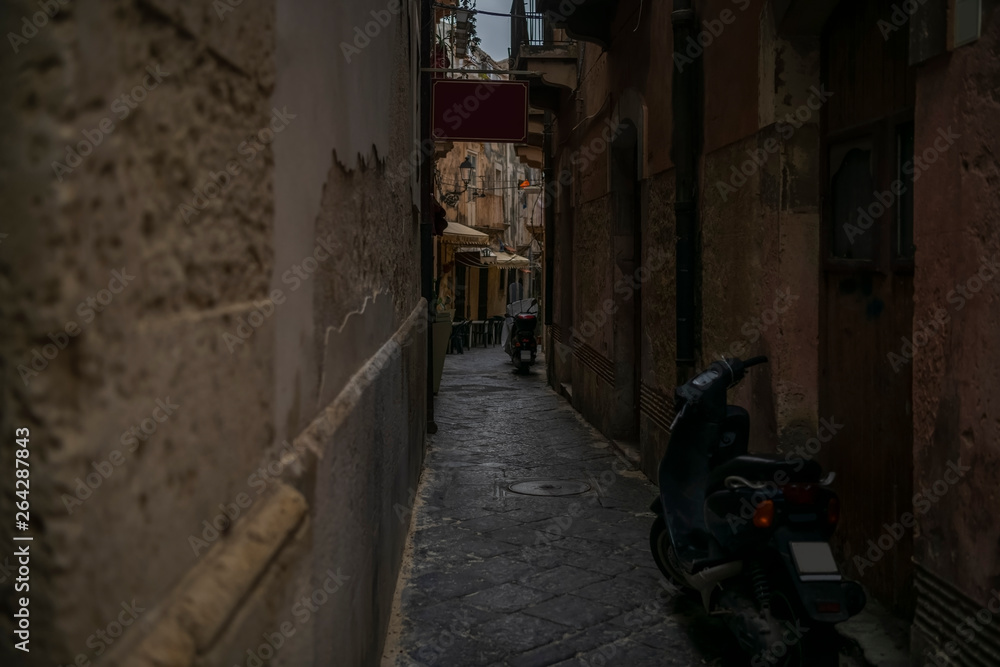 Empty narrow typical for Italy street with motorbikes in Ortigia island in Syracuse, Sicily, south Italy