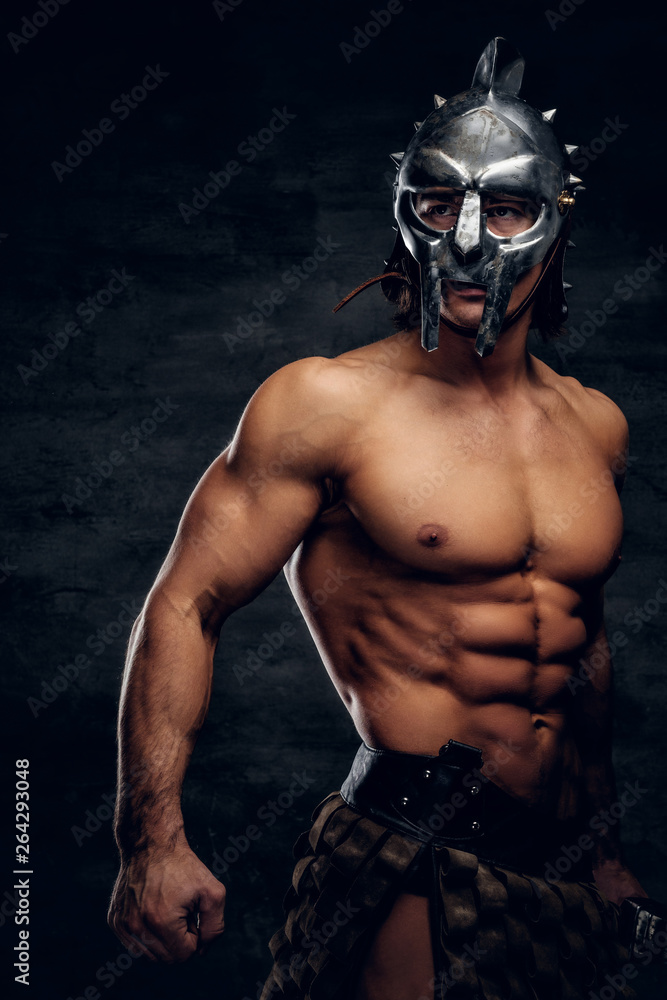 Strong shirtless gladiator in helmet is showing his muscules. He is wearing bandage.