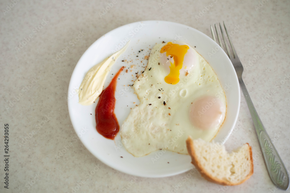 Breakfast in the form of egg with sauces on a white plate