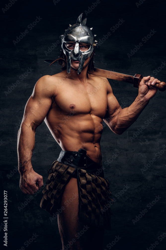 Powerful athlete with sword in his hands. He is wearing gladiator's bandage and helmet.