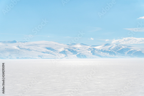 frozen lake with surrounding snow covered rocky mountains 