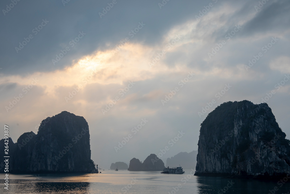 Sunset over cruise ship in karst rock foramtions in Ha Long Bay Vietnam