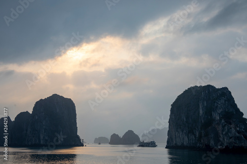 Sunset over cruise ship in karst rock foramtions in Ha Long Bay Vietnam