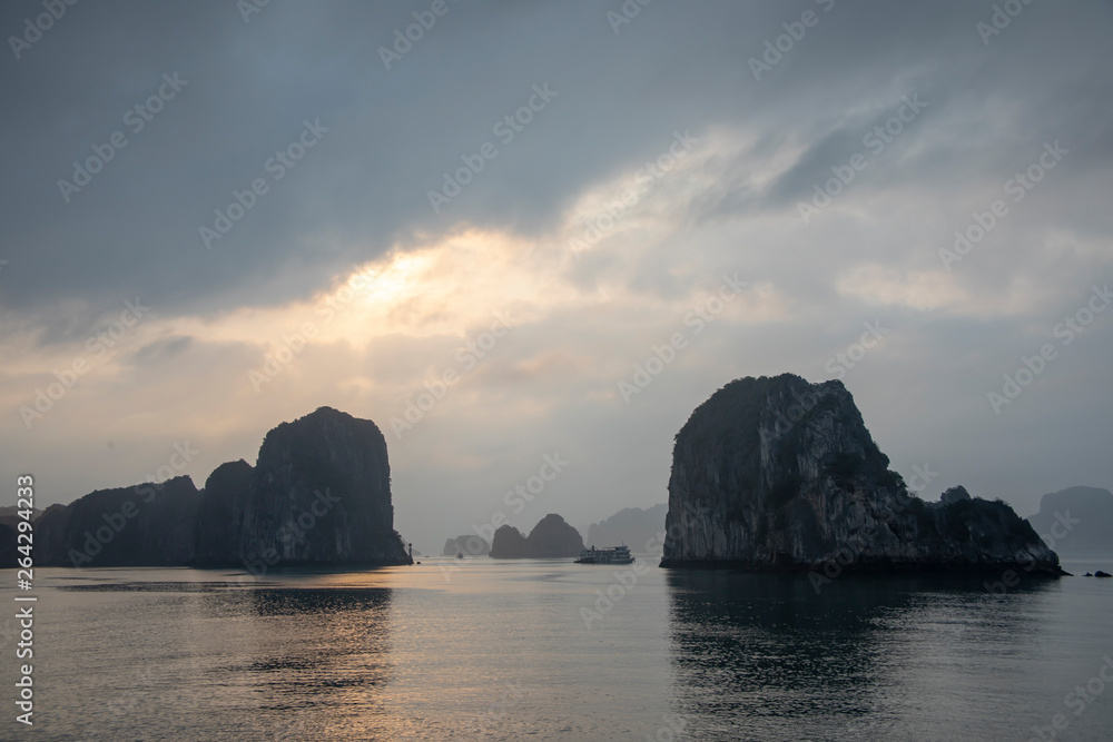 Cruise ship at sunset between karst rock foramtions in Ha Long Bay Vietnam