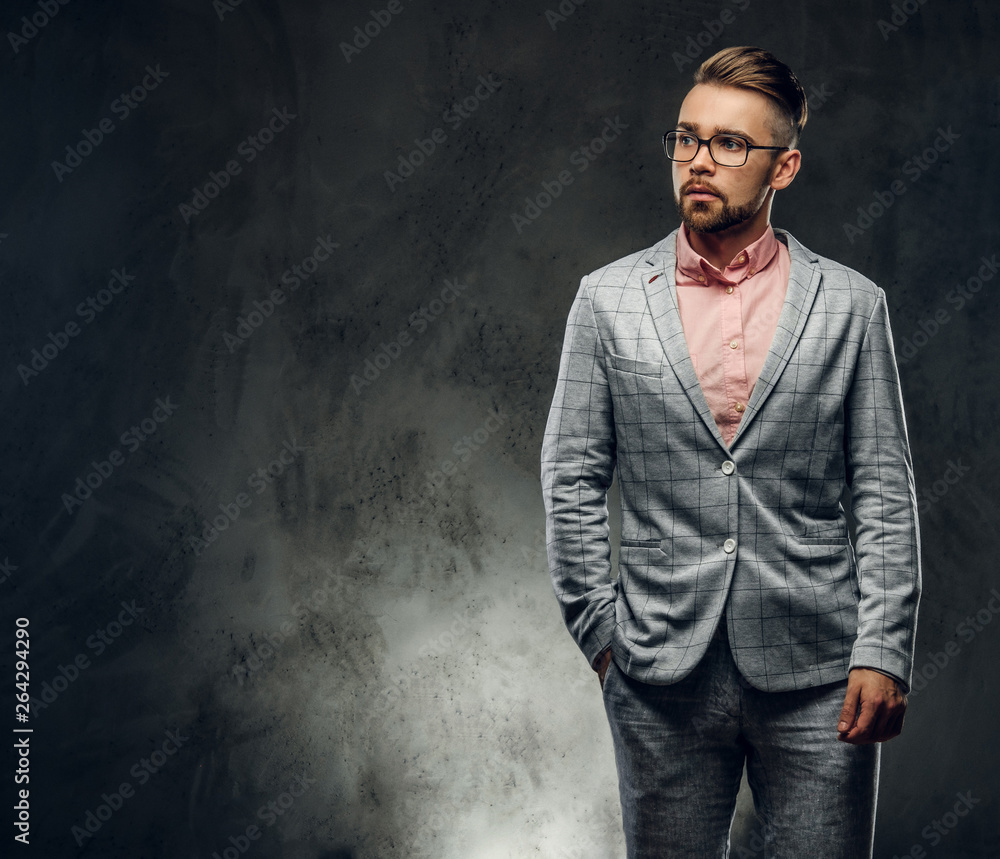 Studio shoot of styilish attractive man in checkered suit, glasses and pink shirt. He put one hand to his pocket.