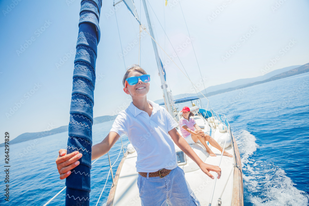 Little boy with his mother having fun on board of yacht on summer cruise. Travel adventure, yachting with child on family vacation. Little boy with his mother having fun on board of yacht on summer cruise. Travel adventure, yachting with child on family vacation.