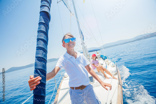Little boy with his mother having fun on board of yacht on summer cruise. Travel adventure, yachting with child on family vacation. photo