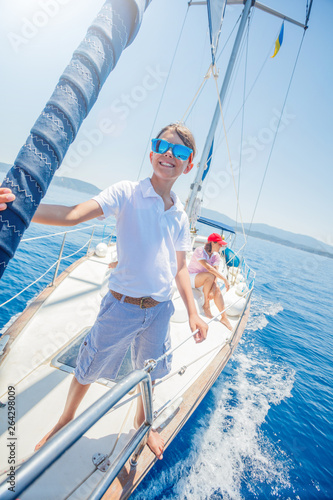 Little boy with his mother having fun on board of yacht on summer cruise. Travel adventure, yachting with child on family vacation.