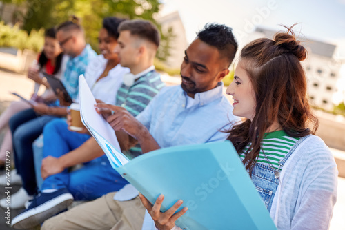 education and people concept - group of happy students with notebooks learning outdoors
