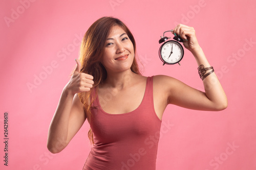 Young Asian woman show thumbs up with a clock. © halfbottle