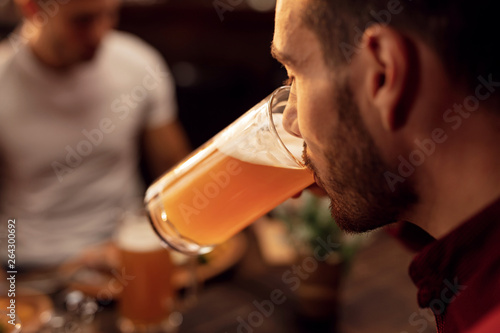 Fototapet Close up of man drinking beer in a bar.
