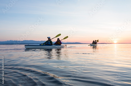 Foto Group of people friends sea kayaking together at sunset in beautiful nature