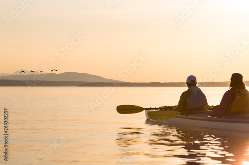 Two women in a sea kayak bird watching. People enjoying healthy lifestyles, nature and wildlife.