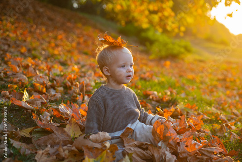 Child autumn leaves background. Warm moments of autumn. Toddler boy blue eyes enjoy autumn. Small baby toddler on sunny autumn day. Warmth and coziness. Happy childhood. Sweet childhood memories