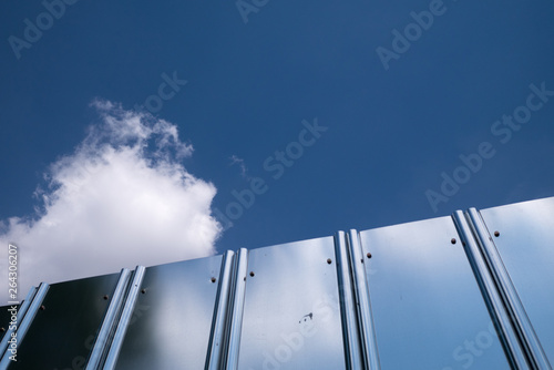 A stainless fence reflects the sky