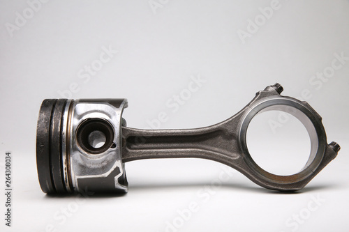 old piston with a connecting rod on a white background. used piston with soot on a white background