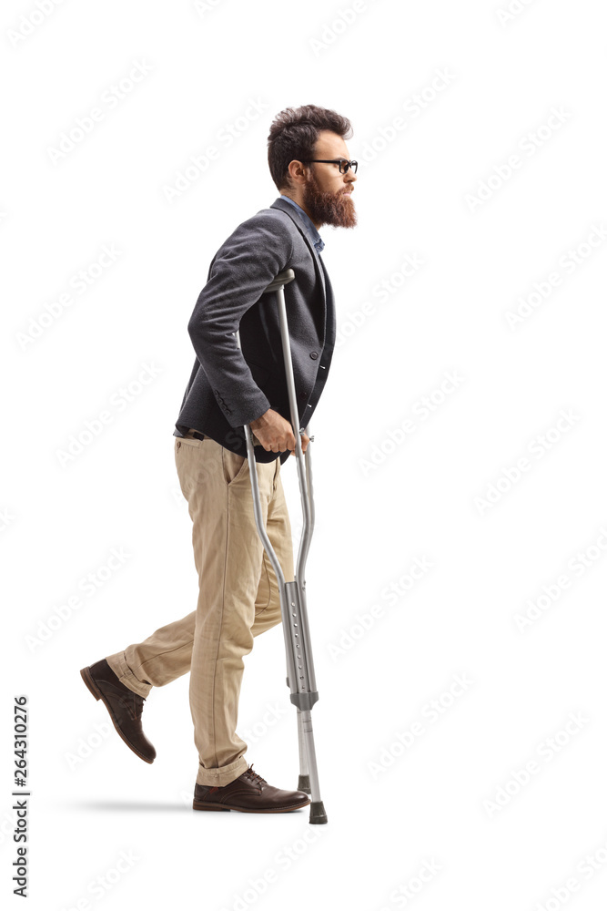 Young bearded man walking with crutches Young bearded man walking with crutches