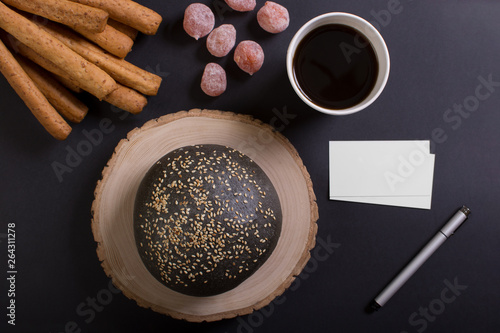 Cup of coffee whith lump of sugar and some candy. Black loaf and breadstick. Top view with copyspace for your text. photo