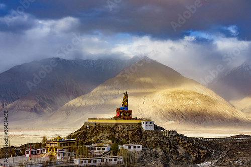 The Maitreya Buddha statue with Himalaya mountains in the background from Diskit Monastery or Diskit Gompa, Nubra valley, Leh Ladakh, Northen India. photo
