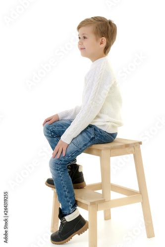 A little boy is sitting on a chair.