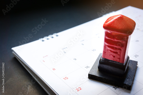 Close up red toy post box on the monthly planner calendar on black background. Summer calendar schedule. Calendar scheduling for travel,holiday and vacation planning or business concept.