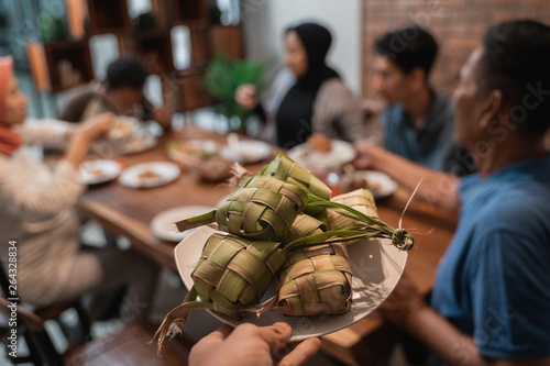 Foto close up of ketupat with people eating dinner on the background