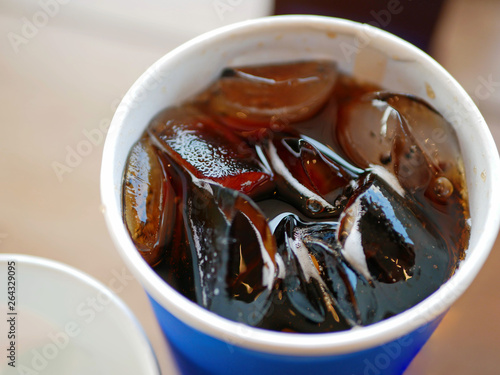 Selective focus and close up of a cub of refreshing carbonated soft drink with ice on a table photo