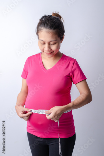 Pregnant women wear pink shirts. who measured her stomach with a tape measure on a white background