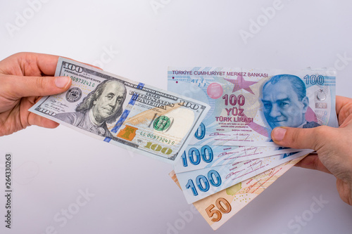 Hands holding American dollar banknotes and Turksh Lira banknotes side by side photo