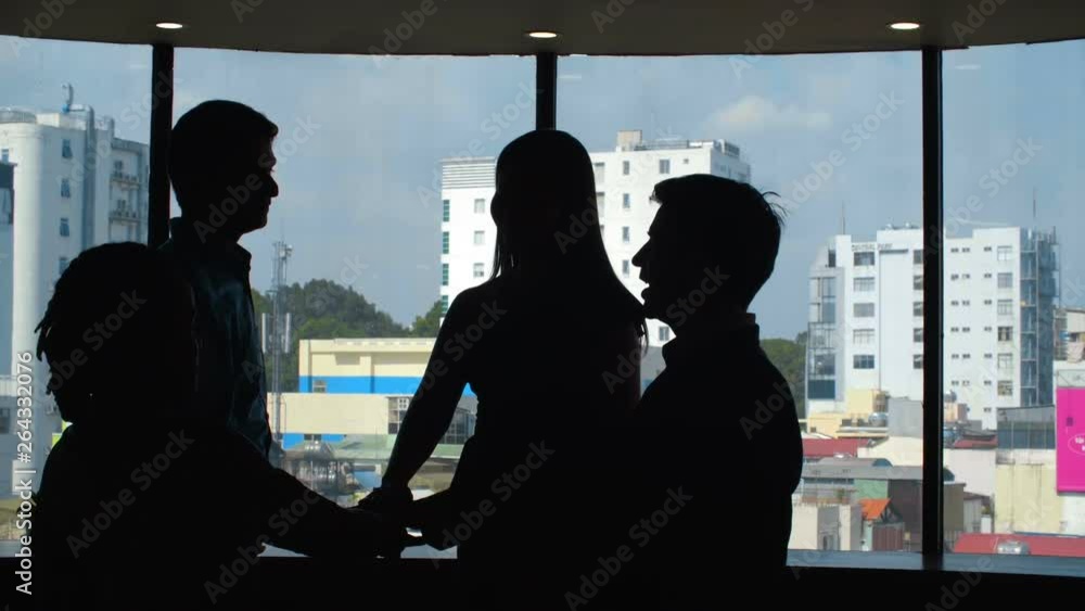 Lockdown of business colleagues standing at window and stacking hands together Lockdown of business colleagues standing at window and stacking hands together